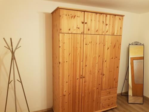 um armário de madeira num quarto ao lado de uma parede em Müller´s Ferienwohnung em Neuhof