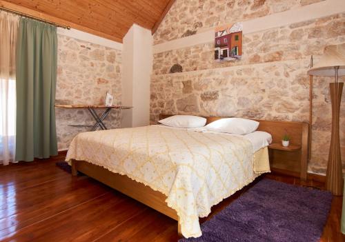 1 dormitorio con cama y pared de piedra en Dalmatian Stone House, en Isla Krapanj