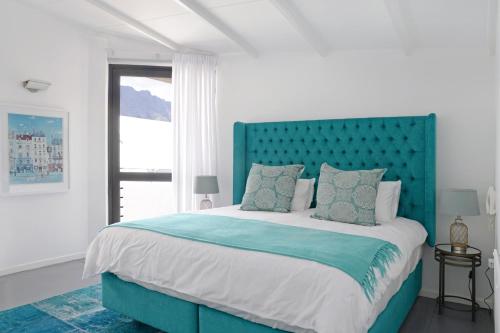 un letto con testiera blu in una camera bianca di No. 6 The Yard a Franschhoek