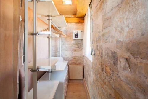 a bathroom with two sinks and a stone wall at Elegant 2-Villa Stone Estate with Pool & Sea Views in Agia Pelagia