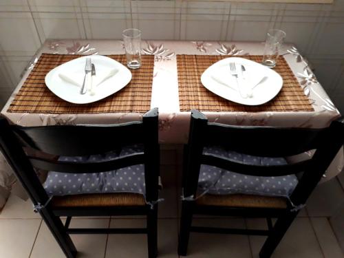 a table with two chairs and a table with two white platesurrencyangering at Sitia Holidays 1 in Sitia