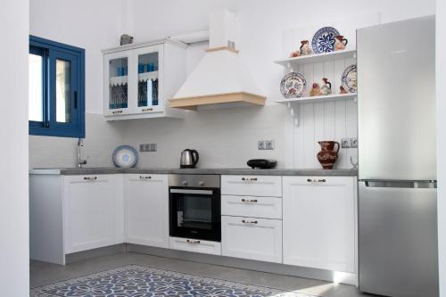 a white kitchen with white cabinets and a refrigerator at Aelia Luxury Villa in Amoopi