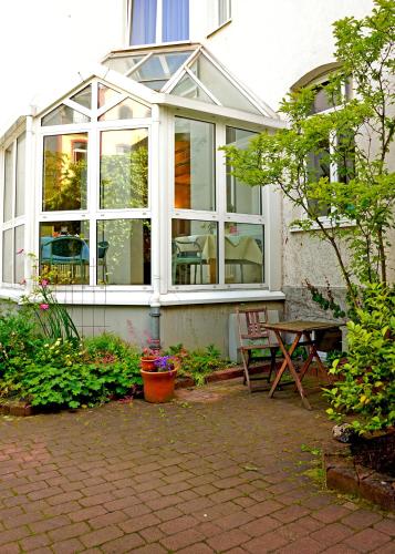 a conservatory with a table and a bench in a garden at Hotel zum Scheppen Eck in Wiesbaden