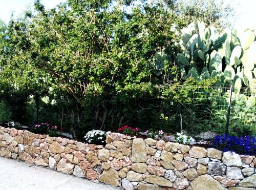 a stone wall in front of a garden at Villette di Scopello - Casa Vacanze in Scopello