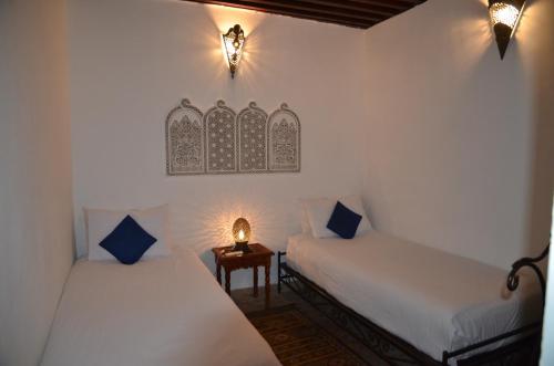 a room with two beds and a table with a lamp at Riad Jamaï in Fès