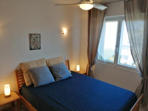 a bedroom with a bed with blue sheets and a window at Guillaumont Apartment in Juan-les-Pins