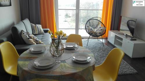 コウォブジェクにあるApartament Feniks Kołobrzeg Aqua Paradiseのリビングルーム(テーブル、黄色い椅子付)