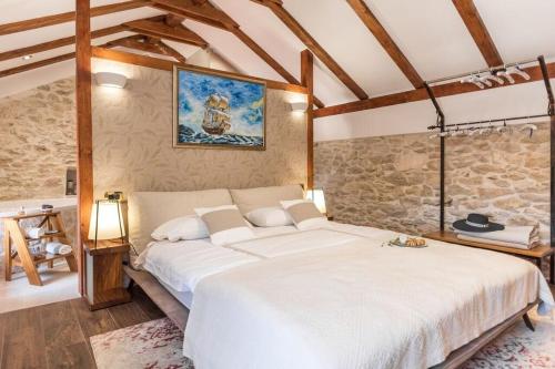 a bedroom with a large white bed and a stone wall at Villa Hirundo Rustica in Skradin