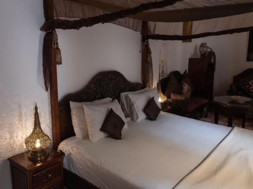 a bedroom with a canopy bed with pillows at Riad Jamaï in Fès