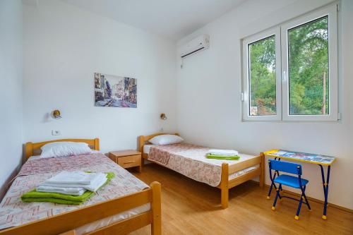 a bedroom with two beds and a desk and two windows at Villa KOSTA in Donji Morinj