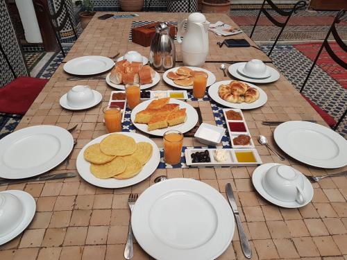 una mesa con platos blancos de comida. en Riad Jamaï en Fez