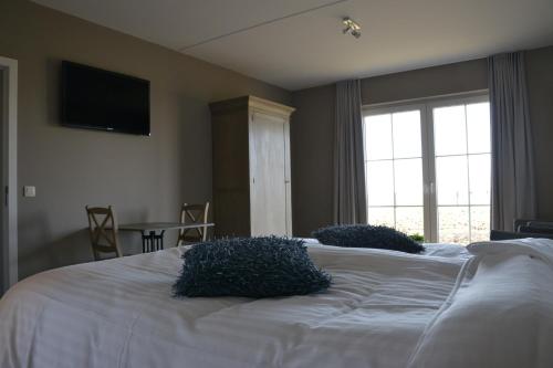 a bedroom with a white bed with two pillows on it at B&B Nieuwhof in Gistel