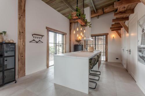 a kitchen with a white island in a room with wooden ceilings at De Wijnlodge in Kootwijkerbroek
