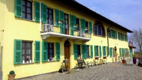 a yellow and green building with green shutters at Villa "Piemonte" in Tigliole