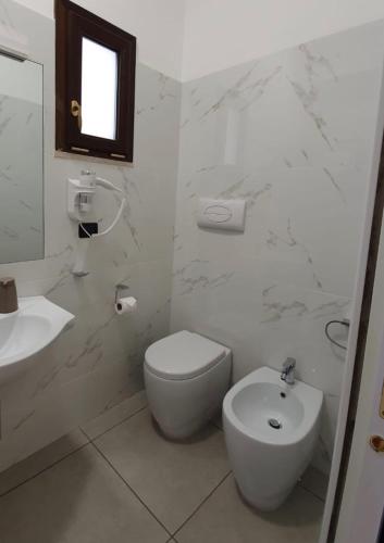 a white bathroom with a toilet and a sink at Guest House Piazza Carmine in Reggio Calabria