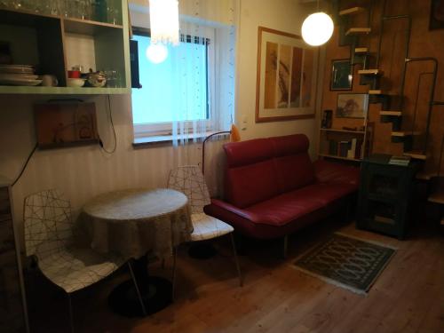 Una sala de estar con un sofá rojo y una mesa. en Zentrales kleines Appartment, en Klagenfurt