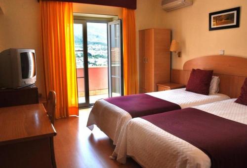 Habitación de hotel con 2 camas y TV en Hotel Solneve, en Covilhã
