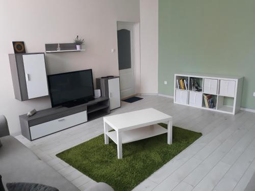 a living room with a tv and a white table at HEMNES Apartman in Kaposvár