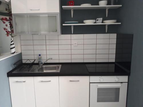 a kitchen with white cabinets and a sink at HEMNES Apartman in Kaposvár