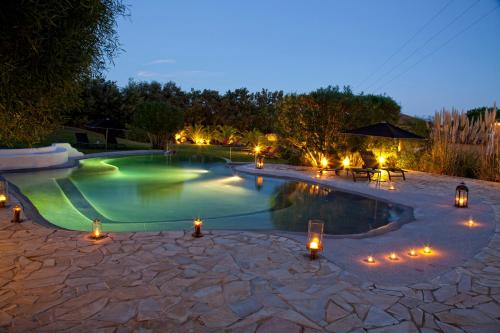 una piscina notturna con candele e luci di La Vigne de Ramatuelle a Ramatuelle