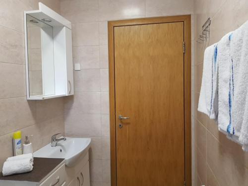 a bathroom with a wooden door and a sink at Apartment GEA 1 in Novi Sad