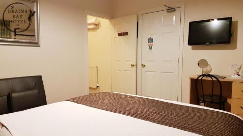 a bedroom with a bed and a tv on the wall at Grains Bar Hotel in Oldham
