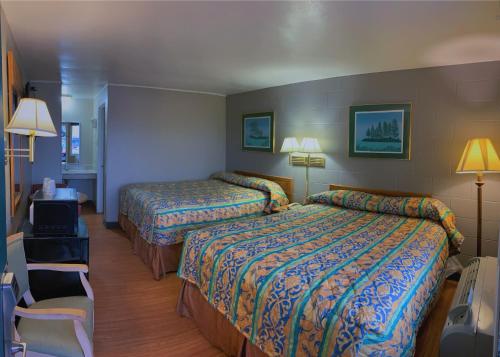 una habitación de hotel con 2 camas y una silla en Super 7 Inn, en Wright City