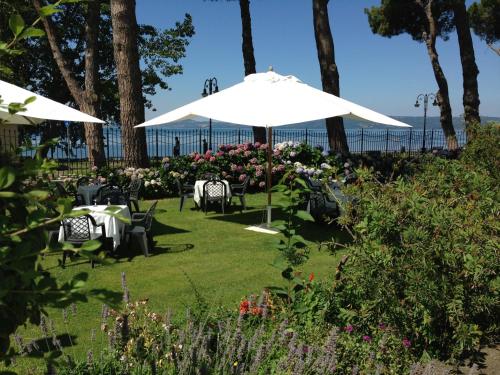 a table and chairs under an umbrella in a garden at Hotel Holiday Sul Lago in Bolsena