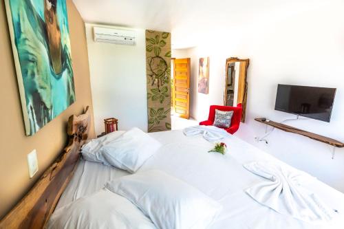a bedroom with a white bed and a tv at Xainã Pousada de Charme in Cumbuco