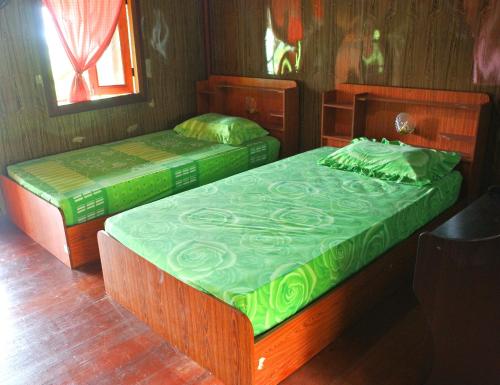 two twin beds in a room with wooden walls at Easy Life Bungalows in Haad Yao