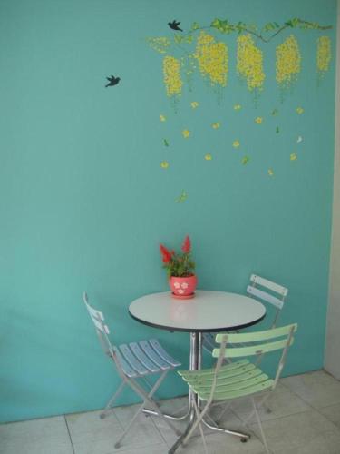 a table and chairs in a room with a blue wall at Pakchong Phubade Hotel in Pak Chong