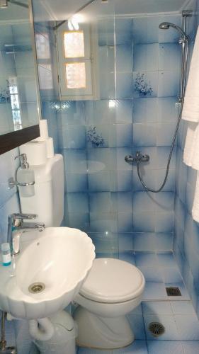 a blue tiled bathroom with a toilet and a sink at Sea Whispers Beach House in Alykes
