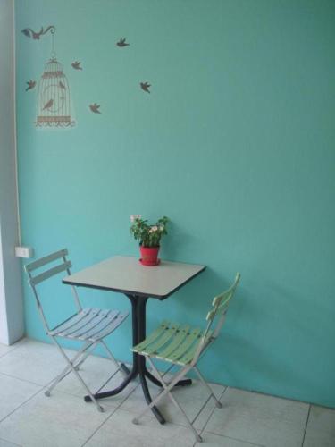 a table with two chairs and a bird cage on a wall at Pakchong Phubade Hotel in Pak Chong