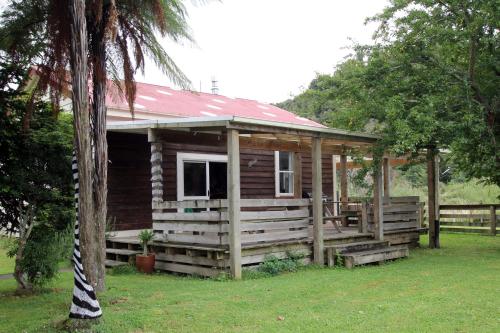 a small wooden cabin with a red roof at Whanga Bridge House in Whangamomona