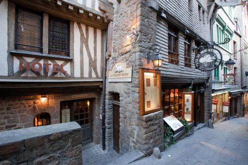 a building with a clock on the side of a street at Le Mouton Blanc in Le Mont Saint Michel