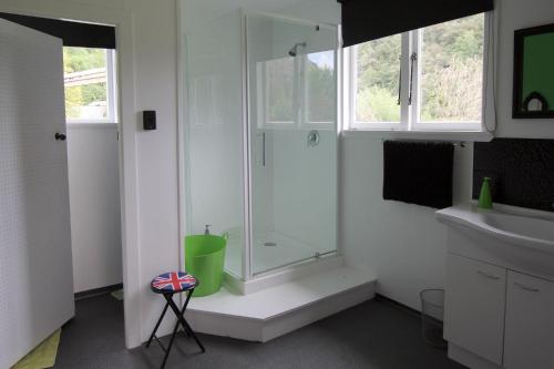 uma casa de banho branca com um chuveiro e um lavatório. em Whanga Bridge House em Whangamomona