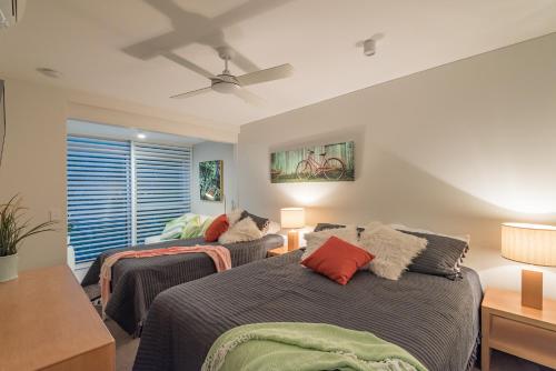 een slaapkamer met 2 bedden en een plafondventilator bij Anchorage - Riverfront Luxury on Gympie Terrace in Noosaville