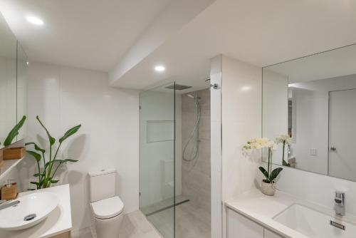a bathroom with a toilet and a sink and a shower at Anchorage - Riverfront Luxury on Gympie Terrace in Noosaville