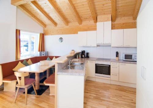 cocina con armarios blancos y techo de madera en Penthouse Kurz, en Westendorf