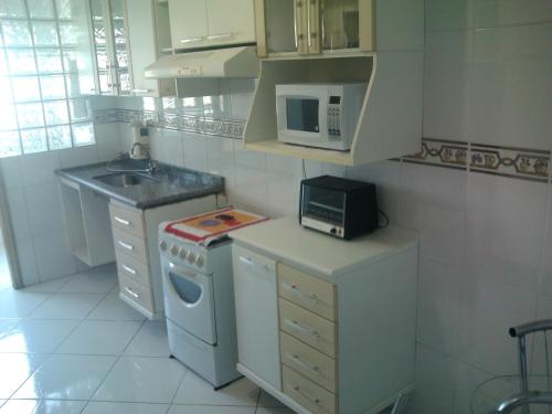 a small kitchen with a stove and a microwave at Apto PROX PRAIA 2 VAGAS GARAGEM, CHURRASQUEIRA SACADA, 3 DORM-GUILHERMINA in Praia Grande