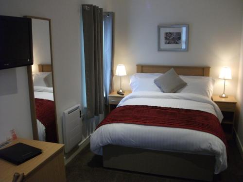 a hotel room with a large bed and a mirror at The Burlington Hotel in Cleethorpes