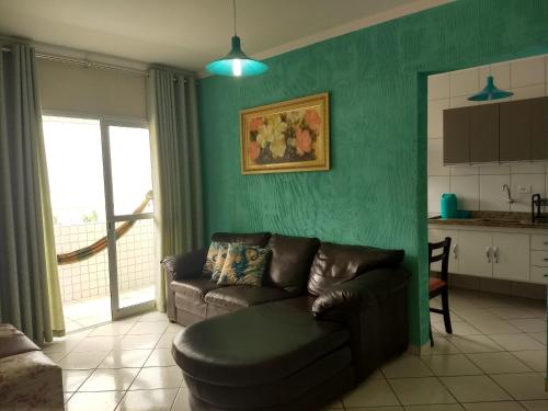 a living room with a couch and a kitchen at Apto Verde Água in Mongaguá