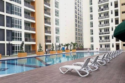 - une rangée de chaises longues blanches à côté de la piscine dans l'établissement Offer Spacious Studio KSL Residences Daya, à Johor Bahru