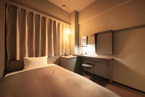 a bedroom with a bed and a desk and a window at Center Hotel Tokyo in Tokyo
