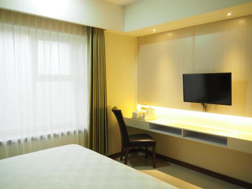 a hotel room with a desk with a tv and a chair at Luminor Hotel Banyuwangi By WH in Banyuwangi