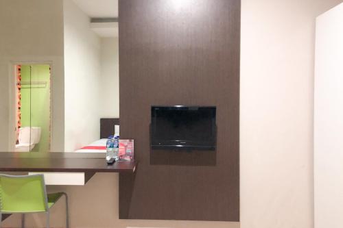 a hotel room with a tv on a wall at RedDoorz near Pantai Pede in Labuan Bajo