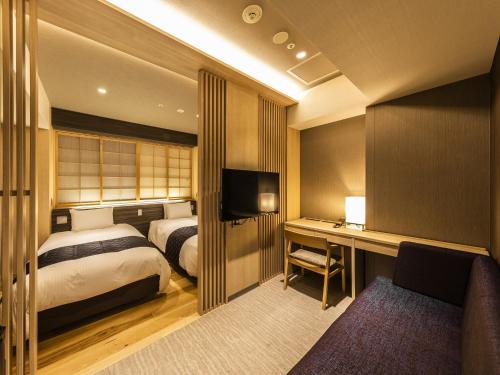 Hotel Elcient Kyoto Hachijoguchi في كيوتو: غرفة نوم بسرير ومكتب مع تلفزيون
