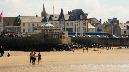 a group of people walking on the beach at Hotel De Normandie in Arromanches-les-Bains