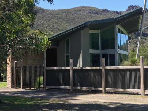 a house with a fence and mountains in the background at Bushland in Halls Gap