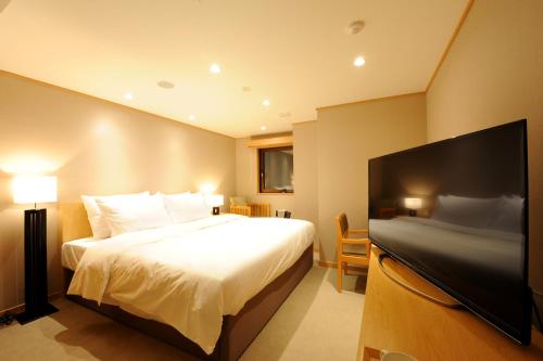 a hotel room with a bed and a flat screen tv at T Hotel Ryuoo in Shimotakai